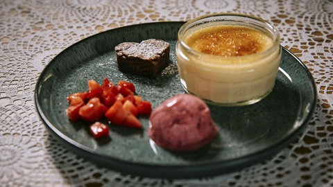 Crème brûleé, Brownie und Himbeereis auf einem Teller