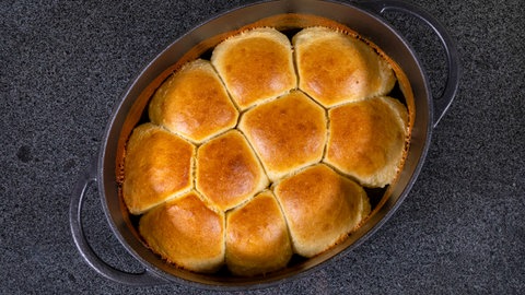 Dir frisch gebackenen Dampfnudeln wurden nach Rezept zubereitet, liegen in einer hitzebständigen Form und können mit Vanillesauce serviert werden. 