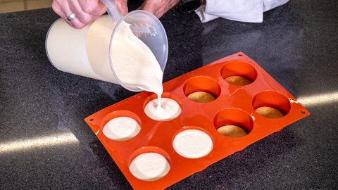 Auf die in den Förmchen ausgelegten Mürbeteig-Kekse wird die Parfait-Masse gegossen.