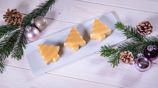 Dreimal Nachtisch: hellgelbe, glänzende Lebkuchenparfait in Tannenbaumform auf einem weißen länglichen Teller