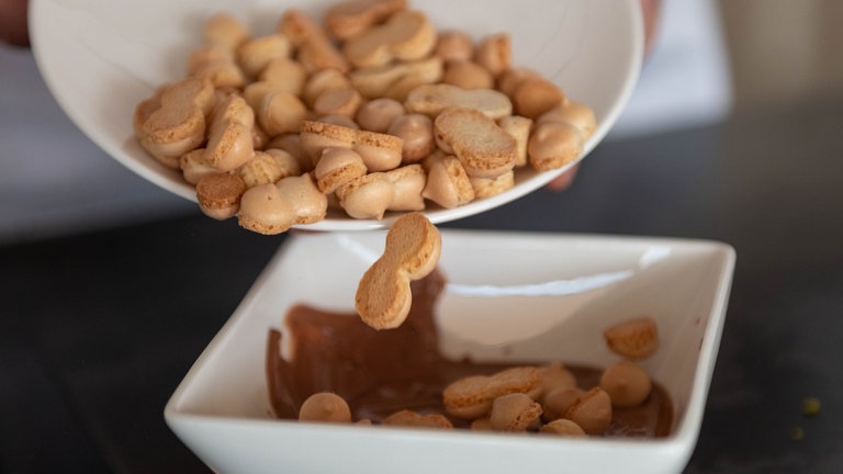 Auf ca. 70 Grad erhitzte Wibele werden zu geschmolzener Schokolade zu gegeben