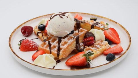 Belgische Waffeln mit Beeren und Eiscreme auf einem Teller angerichtet. Belgische Waffeln sind dicke Waffeln mit tiefem Muster und viel Platz für Toppings wie Beeren, Puderzucker oder Eiscreme. SWR1 Pfännle-Koch Eberhard Braun hat das Rezept für euch.