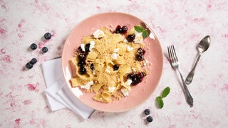 Auf einem Teller angerichtet: Eine süße Pasta-Variante aus Bandnudeln, mit Schichtkäse und Blaubeerkompott.