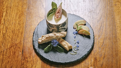 Zitronen-Buttermilch-Dessert mit Gartenfrüchten arrangiert auf einer Steinplatte