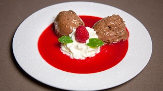 zwei Bollen mousse au chocolat mit Sahne auf Himbeersauce