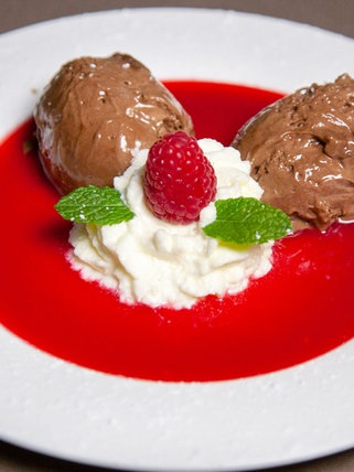 zwei Bollen mousse au chocolat mit Sahne auf Himbeersauce