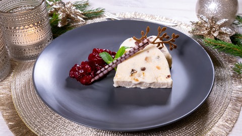 Weihnachtsdessert: Ein cremiges Stollenparfait ist auf einem Teller angerichtet und weihnachtlich dekoriert.
