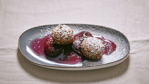 Topfenknödel mit Rotweinzwetschgen auf einem Teller