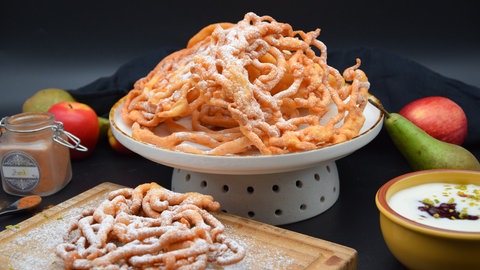 Striebele auf einer Servierplatte, bestäubt mit weißem Puderzucker.