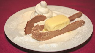 „Weißer Schlitten“ mit Hippenkufen (Apfel-Sahne-Parfait) als Schlitten angerichtet auf einem Teller