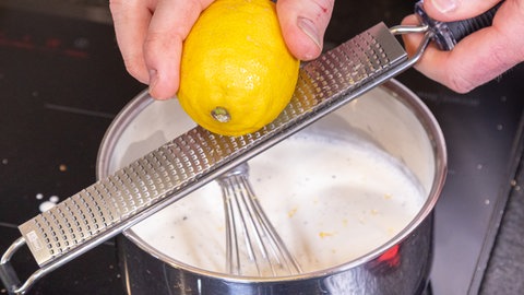 Für das Crème Brûlée wird Zitronenabrieb in die Milch-Sahne-Mischung gegeben.