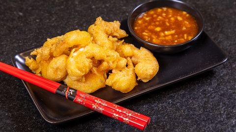 Garnelen im Teigmantel als Fingerfood auf einem Teller angerichtet