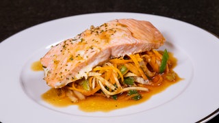 Ein leiches und sommerliches Gericht: Lachs mit Gemüse schön auf einem Teller angerichtet.