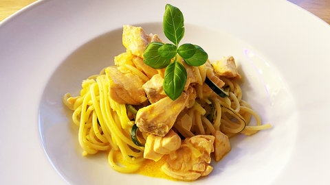 Nudeln mit heller Sauce aus Birne, Zwiebel und Weißwein. Dazu Fisch in Stücken. Obenauf Basilikum als Deko. 