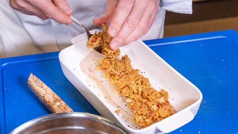 Fisch in Mandelkruste mit Spinat: Auf dem Fisch wird eine Masse aus Paniermehl, Mandeln und Parmesan verteilt.