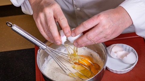 Eier werden in den rohen Pfannkuchenteig gegeben