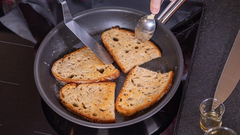 Zwei Scheiben Brot werden in der Pfanne geröstet.