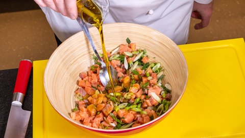 Lachstatar wird in einer Schüssel gemischt und mit Öl übergossen.