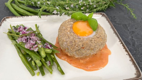 Ei auf Fleischpflanzerl in Tomaten-Rahm-Sauce und Bohnensalat