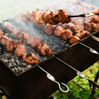 Fleischspieße werden angebraten. Mariniertes Fleisch vom Metzger zum Grillen oder in der Pfanne braten ist meist teurer als abgepacktes vom Discounter. Aber ist es auch besser? 