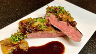 Zwiebelostbraten saftig und zart aus Fleisch vom Rind. Angerichtet auf einem Teller mit Zwiebelschmelze und dunkler Soße. Ein einfaches Rezept.
