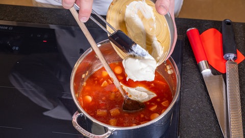Lecker und unkompliziert an Silvester – Rezept für Würstchengulasch: Crème fraîche wird hinzugegeben.