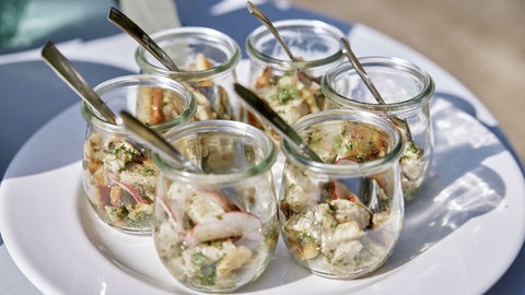 Warmer Weißwurstsalat in Gläsern serviert