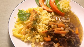 Boeuf Cidre mit Schwäbischen Spätzle und buntem Herbstgemüse auf einem Teller