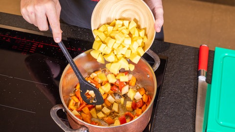 In einem Topf werden Zwiebeln und Gemüsewürfel gedünstet.