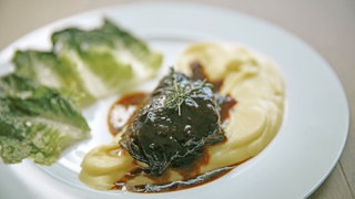 Rinderbäckchen mit Kartoffelpüree und Salat auf einem Teller