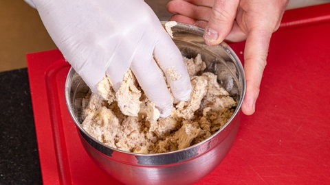 Schweinefilet mit Birnen-Maronen-Gemüse: In einer Schüssel wird der Spekulatius-Crumble für das Weihnachtsmenü geknetet.