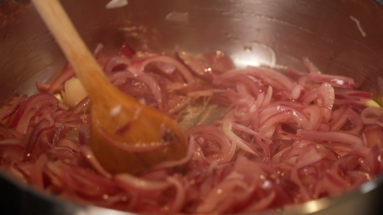Die Zwiebelstreifen werden mit Butterschmalz und Knoblauch bei geringer Hitze glasig angebraten.