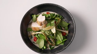 Grünes Curry, angerichtet in dunkler Schale. Mira Mäurer kocht für Marktcheck grünes Curry mit Hähnchenbrust und Kräuterreis.