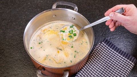 Die gekochte Lauch-Hackfleisch-Suppe in einem Topf. Eine Kelle wurde mit der Suppe befüllt.