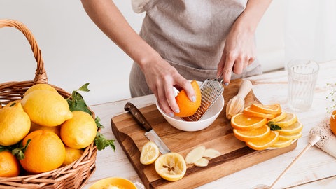 Frau drückt Grapefruit und Orangen aus