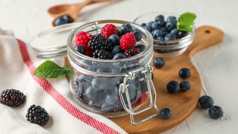 Heidelbeeren, Brombeeren und Himberen in einem Glas. So gesund sind Beeren.