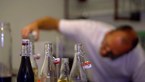 Die Brauerei Härle aus Leutkirch stellt Fruchtsäfte her. Ein Mann arbeitet im HIntergrund, im Vordergrund stehen Flaschen.