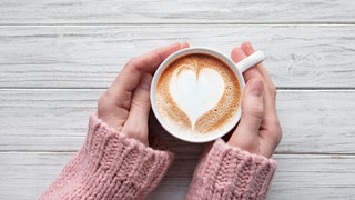 Frau hält eine Tasse Cappuccino