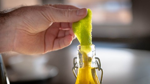 Limettenschalen werden in eine Falsche mit Öl gegeben