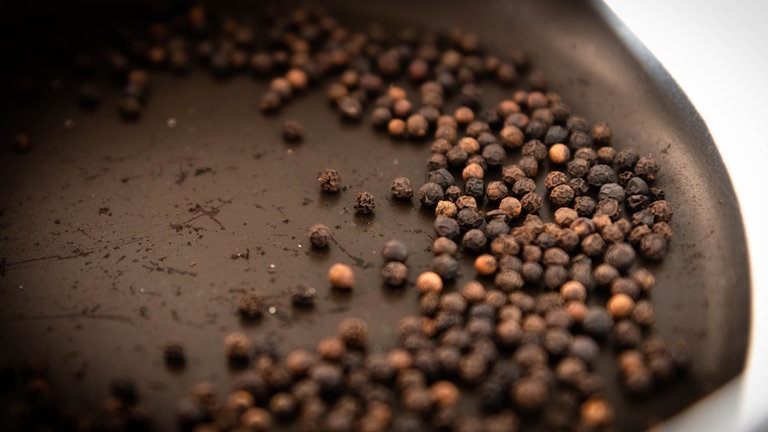 Pfefferkörner werden in einer Pfanne geröstet