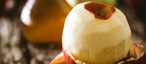 Apfel und Flasche Apfelessig auf Holz