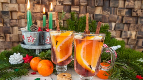 Gläser mit Punsch, Orangen und weihnachtlichen Gewürzen