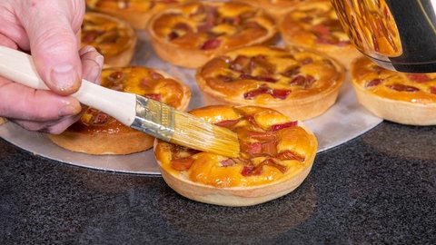 Wie im Rezept beschreiben, werden die Rhabarber Tartelettes nach dem Backen mit Marmelade bestrichen.
