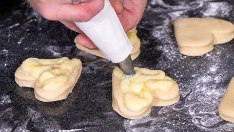 Wie im Rezept beschrieben, wird mit einem Spritzbeutel Pudding auf die Herzen gespritzt.