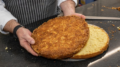 Aus eins mach zwei: Der Hefeteigboden aus der Springform wird in der Mitte sauber durchgeschnitten.