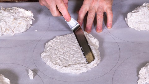 Der Mandelbiskuit-Teig für die Esterhazy-Torte wird, wie im Rezept beschrieben, auf Backpapier gestrichen. Dann kommt er zum Backen in den Ofen.