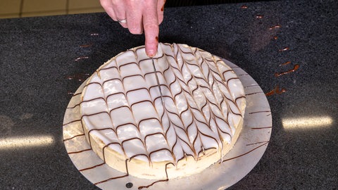 Wie im Rezept beschrieben, wird die Esterhazy-Torte nach dem Backen mit Schokolade verziert. So bekommt sie das original Muster.