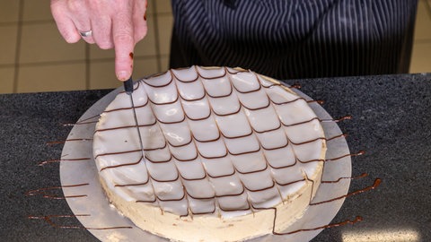 Nach dem Backen wird die Esterhazy-Torte mit flüssiger Schokolade ausdekoriert. Und wie im Rezept beschrieben mit einem Messer das original Muster eingeritzt.