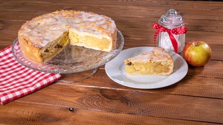 Rezept: Gedeckter Apfelkuchen angeschnitten mit Kuchenstück auf einem Teller.
