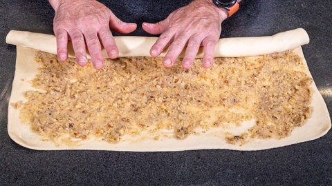 Der mit Marzipan und Walnuss gefüllte Hefeteig wird zusammengerollt. Damit man im Anschluss einen Hefezopf flechten kann. Dieser wird dann zum Hefekranz geformt.